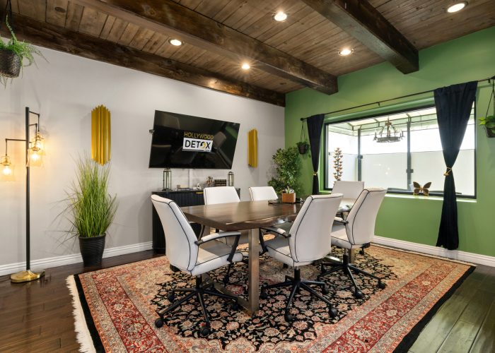 a dining room with a large wooden table, white chairs, and a decorative rug